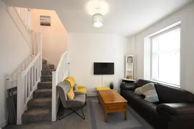 a living room with a couch and a staircase at Hunter Links Cottage in Prestwick