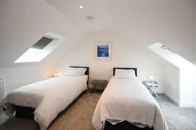 two beds in a room with white walls at Hunter Links Cottage in Prestwick