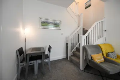 a room with a staircase with a desk and a table at Hunter Links Cottage in Prestwick