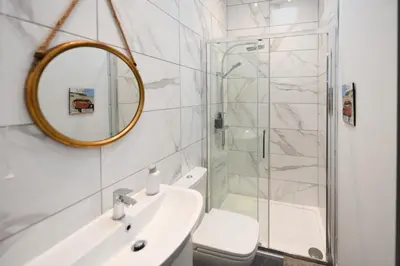 a bathroom with a shower and a sink and a mirror at Hunter Links Cottage in Prestwick