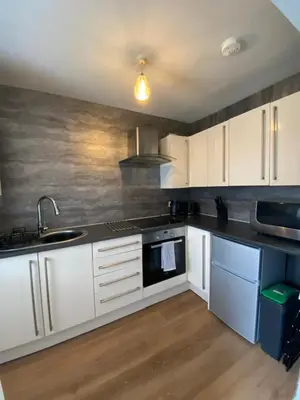 a kitchen with white cabinets and a sink at Shore Cottage in Girvan