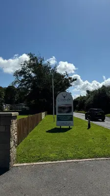 a sign in the grass next to a road at Carlisle CAMELOT HOLIDAY PARK CA65SZ MANOR in Longtown
