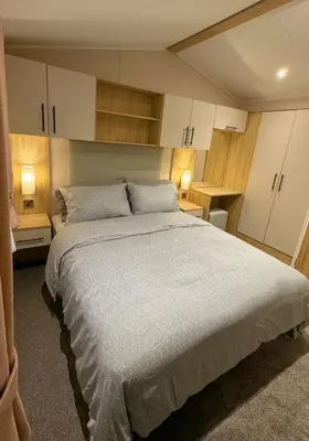 a bedroom with a large bed with white cabinets at Carlisle CAMELOT HOLIDAY PARK CA65SZ MANOR in Longtown