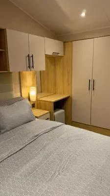 a bedroom with a bed and a desk and cabinets at Carlisle CAMELOT HOLIDAY PARK CA65SZ MANOR in Longtown