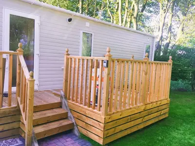 a wooden deck next to a house at Carlisle CAMELOT HOLIDAY PARK CA65SZ Blenheim in Longtown