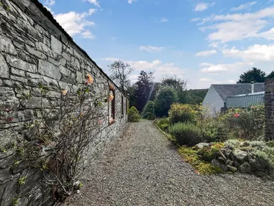 a stone wall with a pathway next to a garden at Arden in Glenluce
