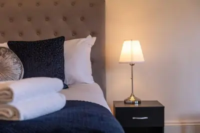 a bedroom with a bed with a lamp and pillows at St Meddans Mews in Troon in Troon