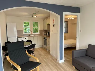 a kitchen and living room with a table and a couch at The Ship Inn's Cabin in Gatehouse of Fleet