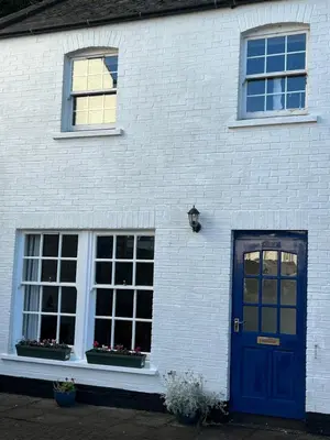 a white brick house with a blue door and windows at The Ship Inn's Cabin in Gatehouse of Fleet