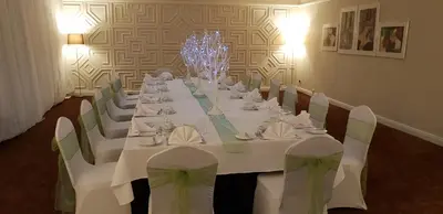 a long table with white tables and chairs in a room at The Empress Hotel in Douglas