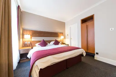 a bedroom with a large bed with purple pillows at The Empress Hotel in Douglas