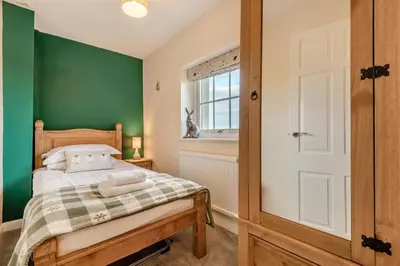 a bedroom with a bed with green walls and a window at 3 Bed in Workington oc-92628 in Dean