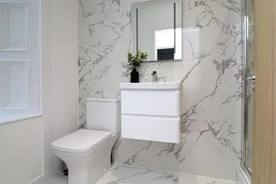 a white bathroom with a toilet and a sink at The Manor - Beachwalk Apartments in Ayr