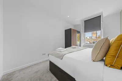 a bedroom with a bed with yellow pillows and a window at The Manor - Beachwalk Apartments in Ayr