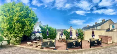 a backyard with a patio with tables and umbrellas at Room with Newly Renovated Private Bathroom above Village Pub Stag Inn Crosby Maryport in Maryport