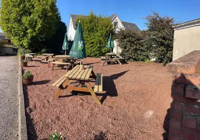 a group of picnic tables and umbrellas in a yard at Room with Newly Renovated Private Bathroom above Village Pub Stag Inn Crosby Maryport in Maryport