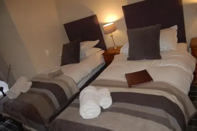 two beds in a hotel room with a book on them at The Boot Inn in Boot