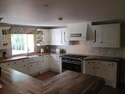 a kitchen with white cabinets and a wooden counter top at Brig o Doon House Alloway in Ayr