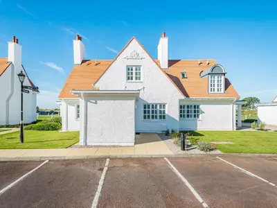 a white house with a garage in a parking lot at Lundin Links - Ukc6916 in Turnberry