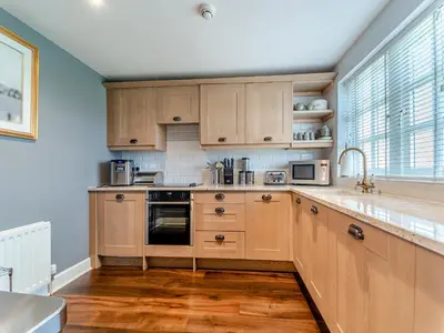 a kitchen with wooden cabinets and a large window at Royal Aberdeen - Ukc6917 in Turnberry