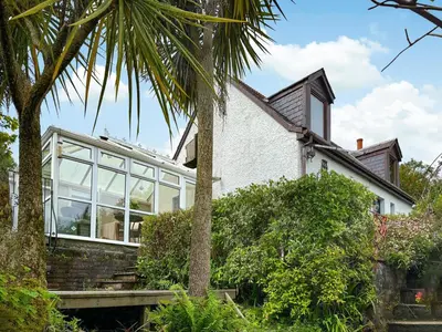 a house with glass windows and a palm tree at The Cottage in Whiting Bay