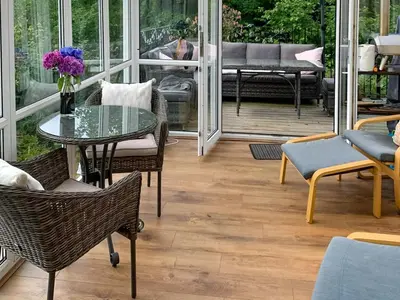 a patio with a glass table and chairs on a porch at The Cottage in Whiting Bay