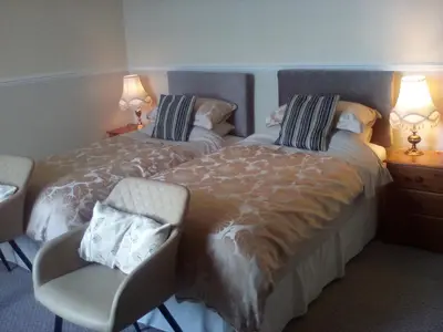 a bedroom with two beds and a chair and two lamps at The Merchants House in Cairnryan