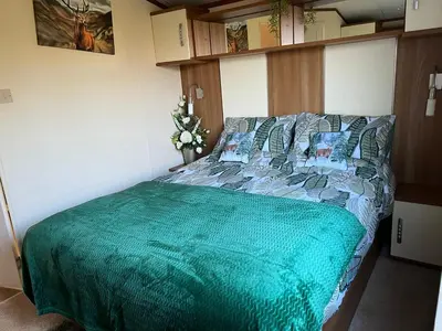 a bedroom with a bed with a green comforter at Maneight Fir View with hot tub in Dalleagles