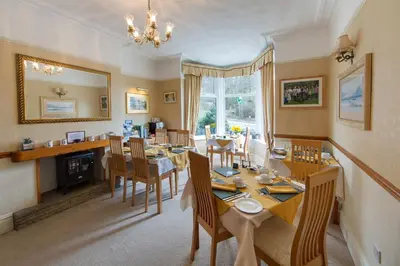 a dining room with a table and chairs and a mirror at Laurel Bank Guest House in Keswick