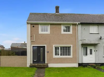 a brick house with white doors and a grass yard at Modern & Stylish 2 Bed Home in Whitehaven in Whitehaven