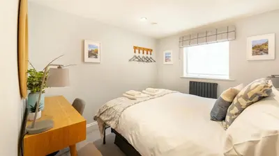a bedroom with a bed and a desk and a window at Derwentwater View in Portinscale