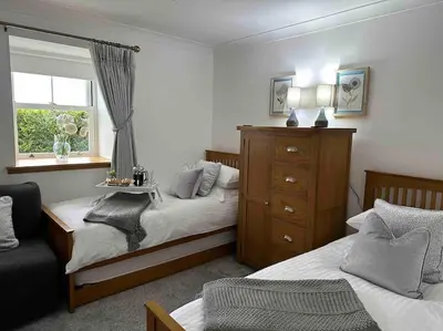 a bedroom with two beds and a window at Bungalow with Hot Tub, BBQ Hut, Golf Net , Large Garden & Play Area in Maybole