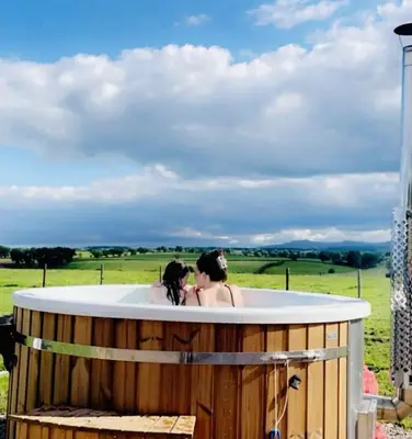 two women in a hot tub in a field at Unit 1 - Dolly Daydream Bell Tent in Carlisle