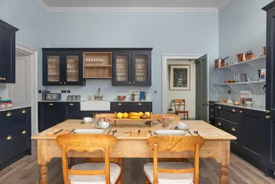 a kitchen with a wooden table with chairs and cabinets at Dabton House in Carronbridge