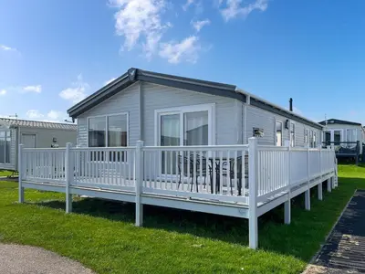 a mobile home with a white porch and a fence at Bud's Bay in Mainsriddle