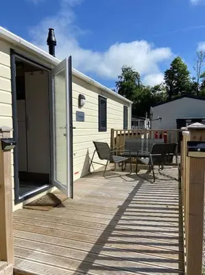 a deck with a table and a grill and a trailer at Rhodes Retreat, Lake District in Brigham