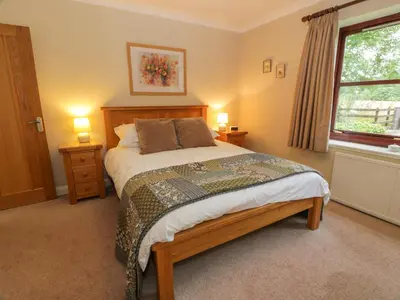 a bedroom with a bed with two night stands and a window at The Barn at Daldorch in Mauchline