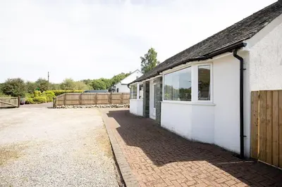 a white house with a brick sidewalk next to a building at SHELTER STONE - Cottage in the heart of the Lakes in Keswick