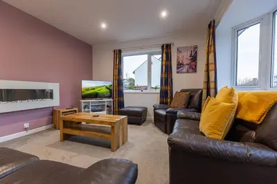 a living room with leather furniture and a flat screen tv at SHELTER STONE - Cottage in the heart of the Lakes in Keswick