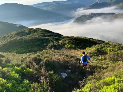 a person walking on a hill with clouds in the mountains at Helvellyn Room With View - Double or twin in Penrith