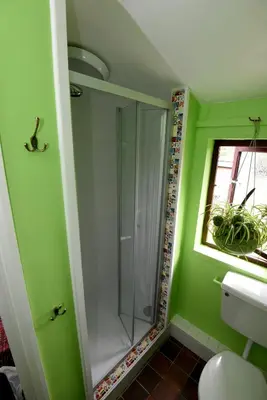 a bathroom with a glass shower in a green wall at Helvellyn Room With View - Double or twin in Penrith