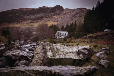 a rocky river with a house in the mountains at Helvellyn Room With View - Double or twin in Penrith