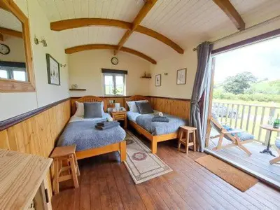 a bedroom with two beds and a balcony at Puddleduck Hut Armathwaite with hot tub and dog agility course, perfect for a romantic break in Armathwaite