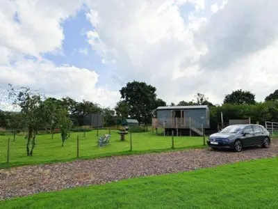 a car parked in a field with a trailer at Puddleduck Hut Armathwaite with hot tub and dog agility course, perfect for a romantic break in Armathwaite