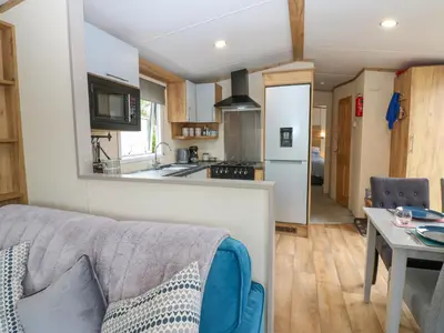 a living room with a couch and a kitchen at Plot 41 in Carlisle