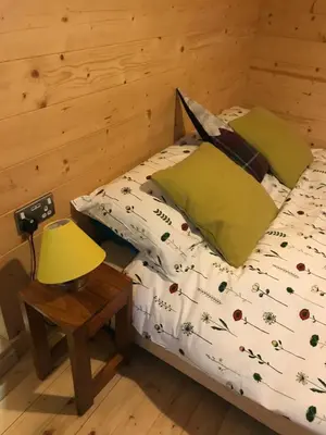 a bed in a room with a lamp on a table at Helvellyn - The Hut - Twin or Double in Glenridding