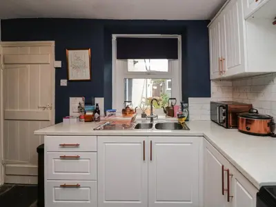 a kitchen with white cabinets and a sink and a window at Whitecroft Nook in Seascale