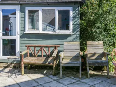 two wooden benches sitting outside of a house at Whitecroft Nook in Seascale