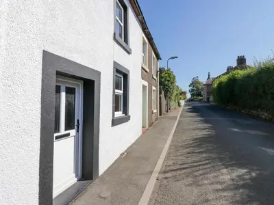 a white building with a door on the side of a street at Whitecroft Nook in Seascale