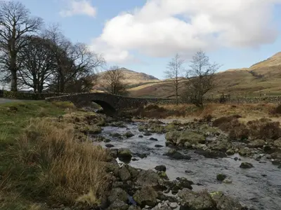 a bridge over a river in a field at Whitecroft Nook in Seascale